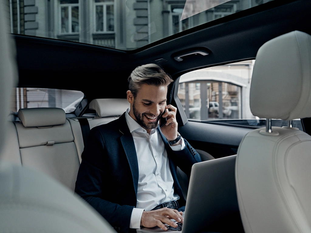 Man in suit talking on phone inside a car.