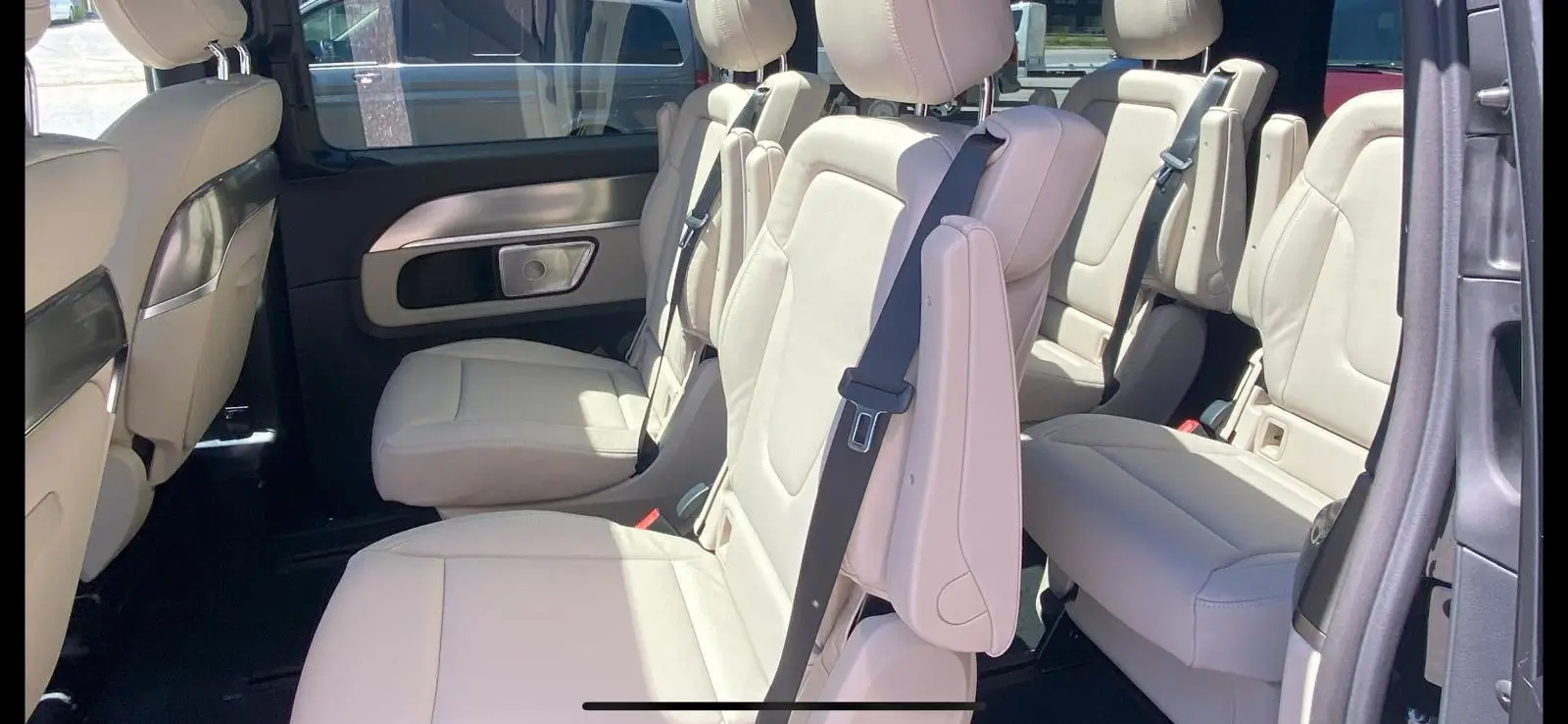 Interior of a car showing white leather seats and seatbelts.