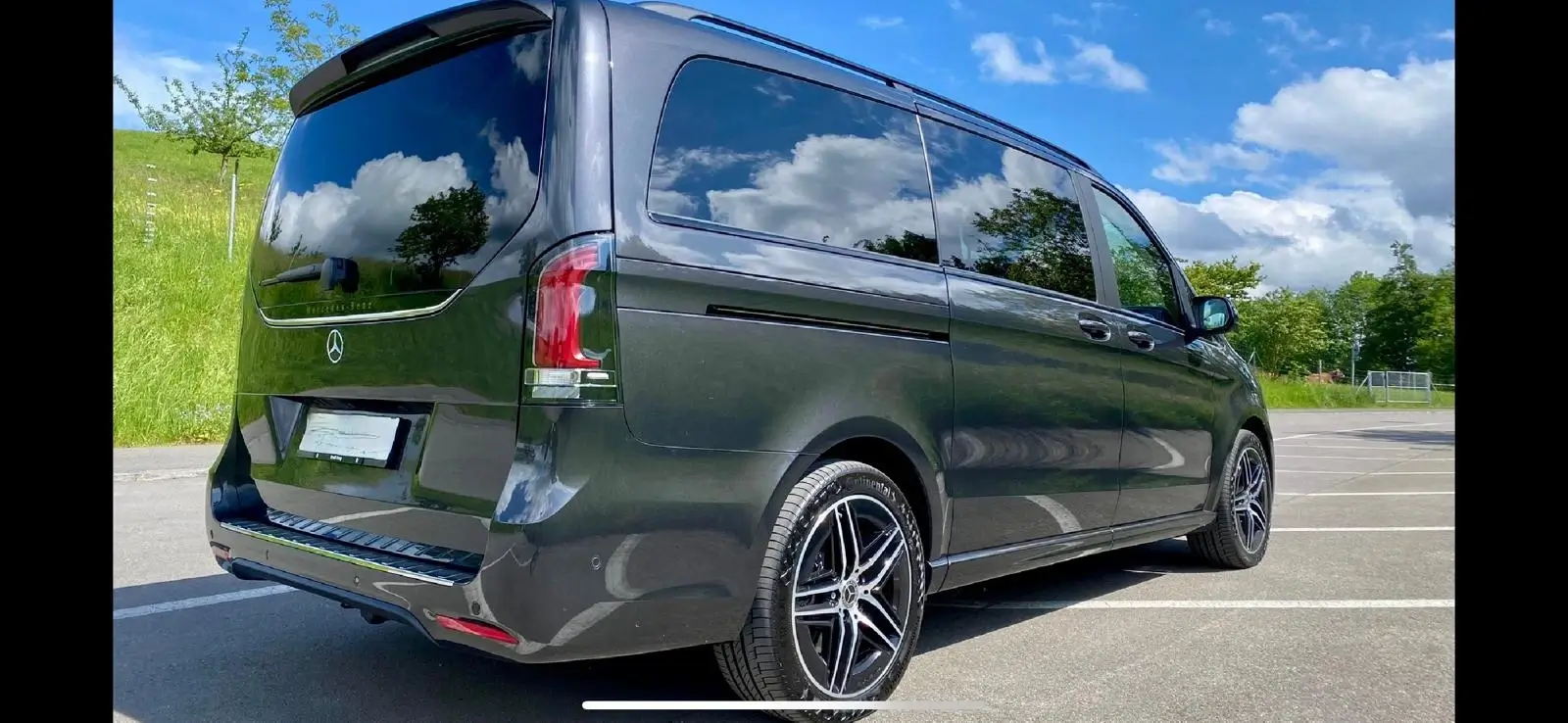 Sleek dark gray van parked outdoors under a blue sky.
