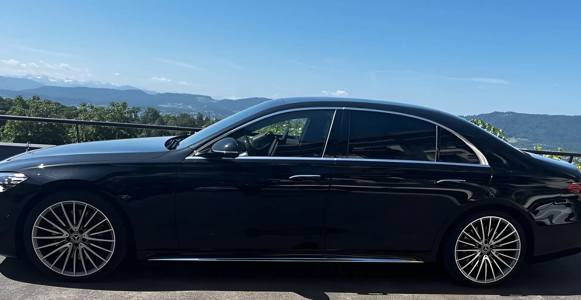 Sleek black sedan parked with a scenic mountain backdrop.