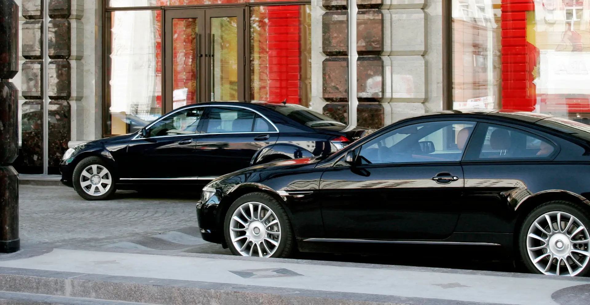 Two black luxury cars parked on a city street.