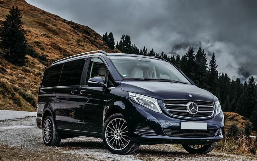 Sleek black Mercedes-Benz van parked on a scenic hillside under a cloudy sky.