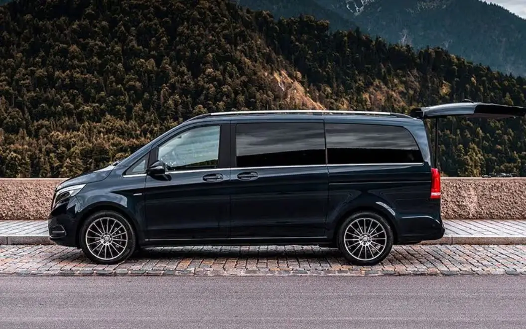 Black luxury van parked by a scenic mountain road.