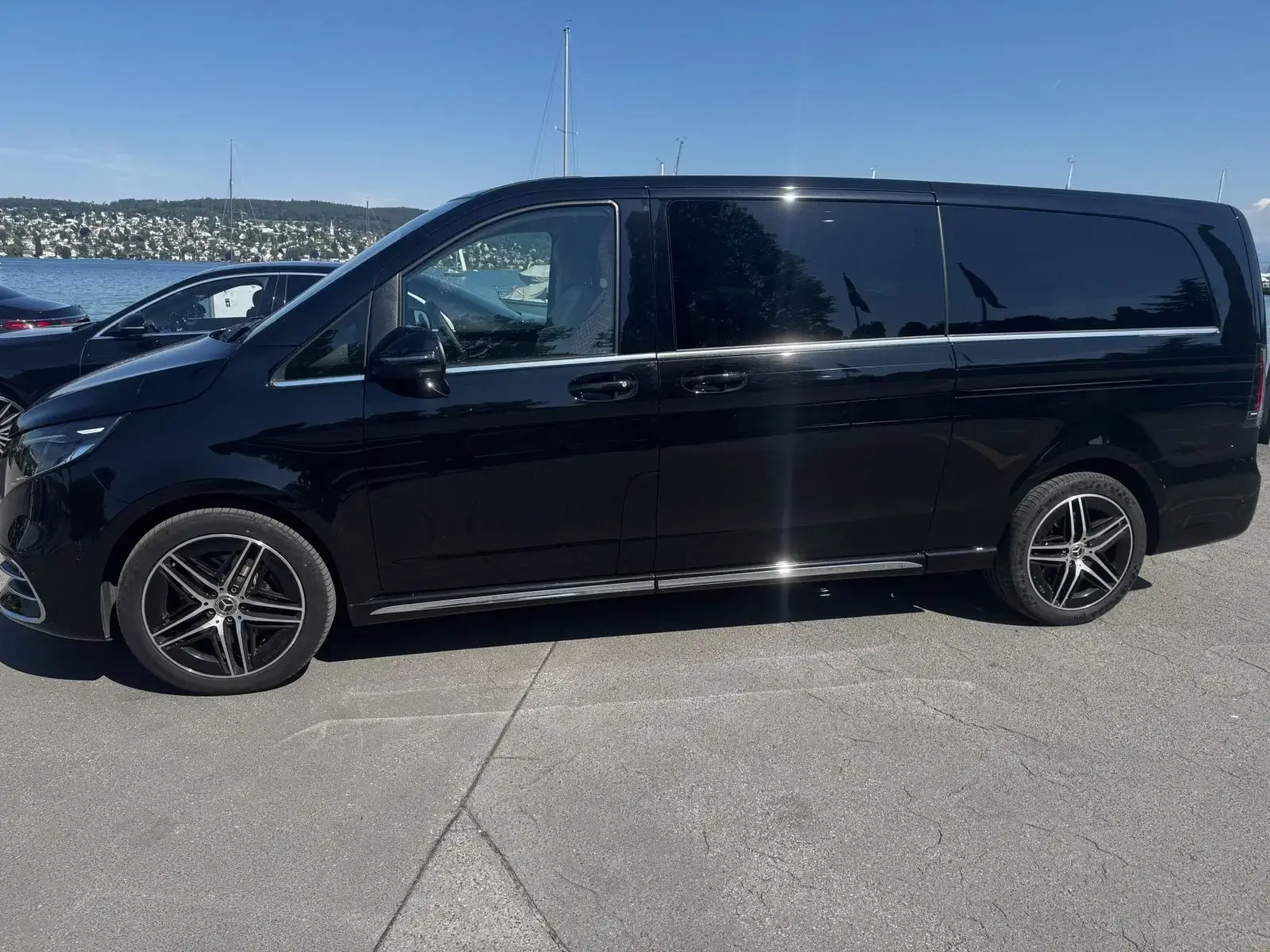 Black luxury van parked outdoors on a sunny day.